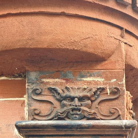 A scupture of a green man on a column capital of a Victorian building in Glasgow.