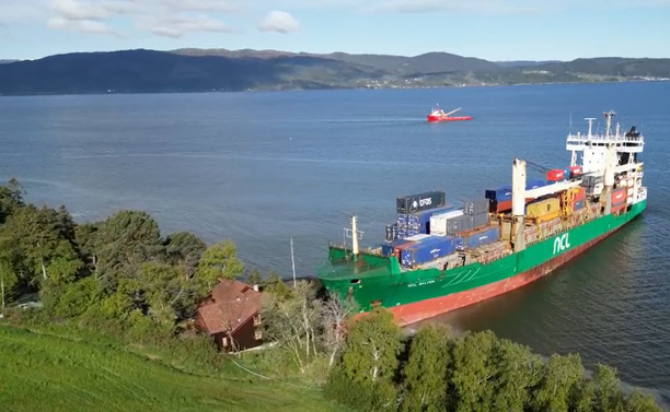 Wide shot of the latest shipping accident with a large container ship just inches away from a house in Norway