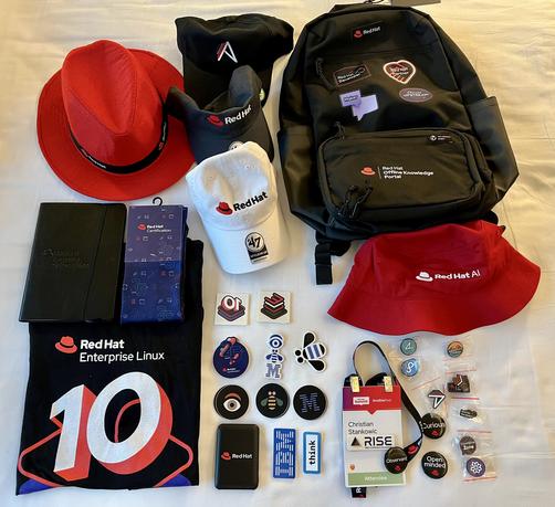 A huge load of swag: 5 caps and hats, numerous stickers and pins, a RHEL 10 shirt and a backpack