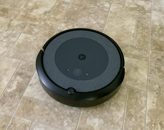 A Roomba robot vacuum happily vacuuming a vinyl floor.