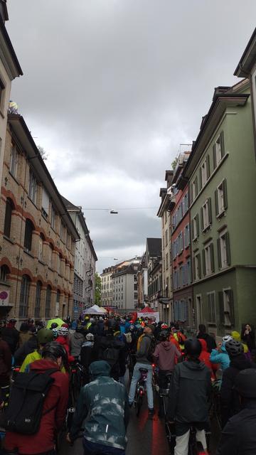 In der Konradstrasse vor dem westlichen Eingang zum Velotunnel stauen sich Velos, weil die Strasse vor dem Tunnel u.a. wegen Ständen schmäler wird. Die Strasse ist nass und es spiegeln sich Velorücklichter darin.