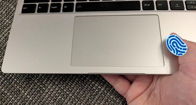 Photo of how to hold the laptop, seen from above, with my (censored) thumb next to the touchpad, and my fingers extending below it.