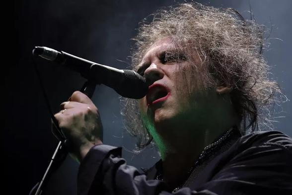A man with lovely hair sings sweetly into a microphone