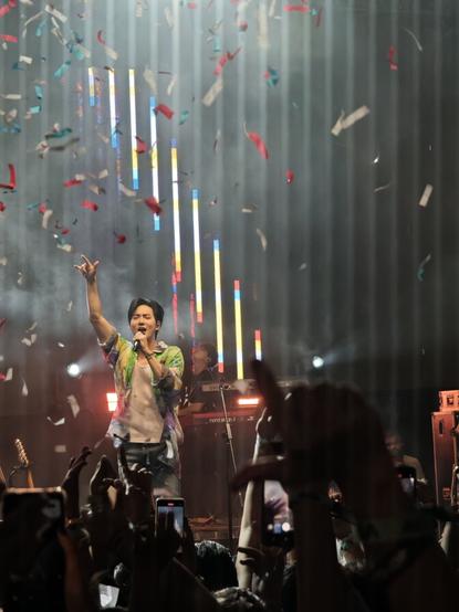 SUHO sings on stage as multicolored confetti showers down onto the crowd.