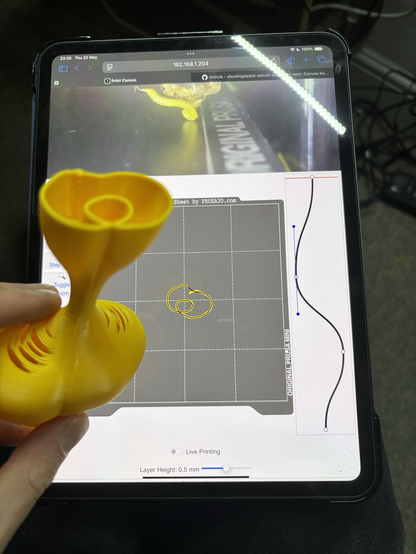 A yellow printed vase held up in front of an iPad showing the sketches that were used to define it