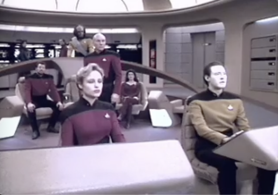 The crew of the Starship Enterprise bask in the redish-purple glow of an oncoming wormhole.