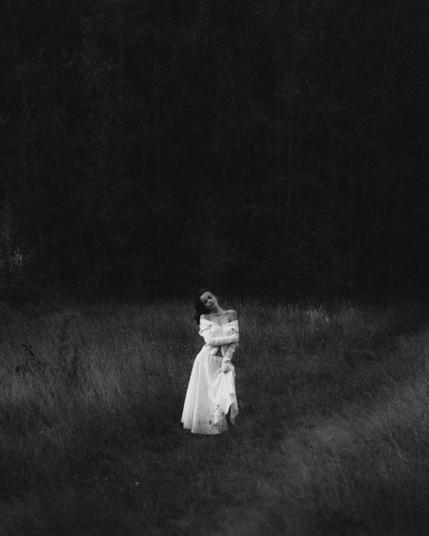 ethereal woman in white dress in dark woodland