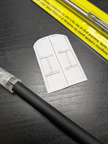 Close up of a white plastic door, flanked by an x-acto knife and a tungsten scribe pen