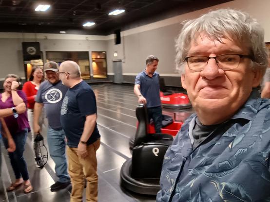 Selfie taken with friends in background and several bumper cars).