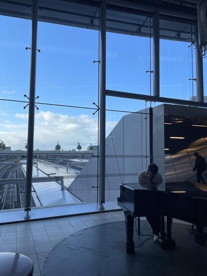 Man playing a grand piano in the public hallway of Utrecht Centraal train station.