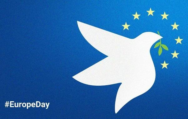 European Day of Peace celebration with people holding peace signs and flags in a vibrant outdoor setting.