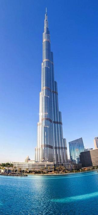 Das Bild zeigt den Burj Khalifa in Dubai, das derzeit höchste Gebäude der Welt. Majestätisch ragt der gläserne Turm in den tiefblauen Himmel, flankiert von moderner Architektur und umgeben von einem künstlich angelegten Wasserbecken. Die Szenerie strahlt monumentale Größe, technische Perfektion und eine fast übermenschliche Gigantomanie aus – ein Symbol für das Streben nach Höherem, das zugleich die Frage nach innerer Substanz aufwirft.

Image Description (English):
The image depicts the Burj Khalifa in Dubai, currently the tallest building in the world. The sleek glass tower rises majestically into the deep blue sky, surrounded by modern structures and bordered by a man-made water basin. The scene radiates monumental scale, technical perfection, and an almost superhuman sense of gigantism – a symbol of mankind’s striving for greatness, while subtly questioning the depth behind such towering ambition.🖖