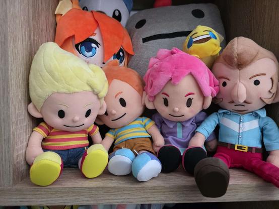 the mother 3 protagonists, unboxed, in my plushie shelf, along with some other, unrelated plushies (and a clay man)