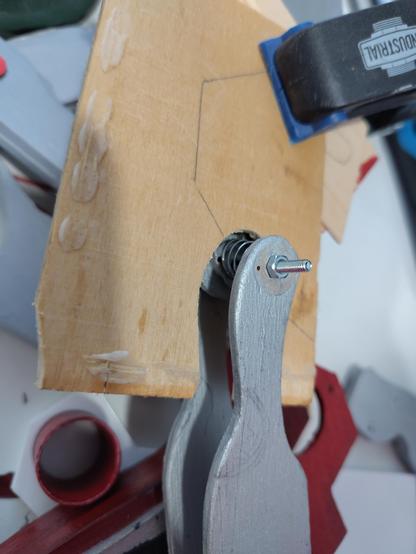 Two identical silver parts with a narrow head. A screw through the heads connect them. A spring is around the screw. There's also a wooden part that has a hole that's exactly the form of the head of one of the silver parts.