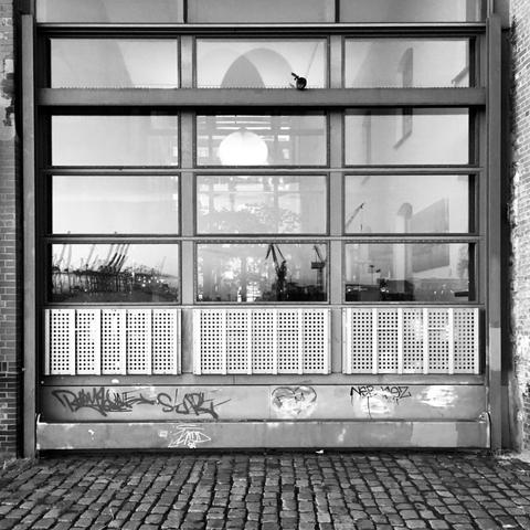 black and white photograph of hamburg harbour reflected in a large window.