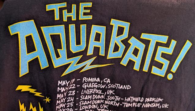 An Aquabats t-shirt with tour dates for 2025. Second day of the tour is in "Glasgow, Scotland". Following dates are cities in England, with the format "City Name, UK".