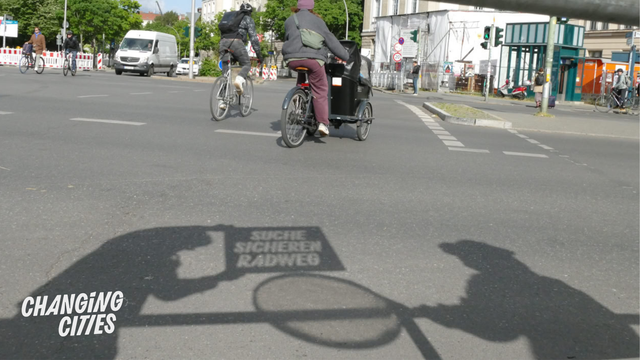Suche sicheren Radweg Schablone wirft Schatten auf eine mehrspurige Straße mit Fahrrädern, aber ohne Radweg