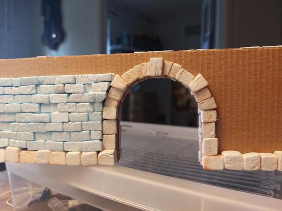 Partial stone wall out of XPS bricks with a lot better stone arch. A lot of cardboard is still showing but I've run out of bricks. It's got a nice capstone and two stones halfway the arch on either side which are a bit bigger