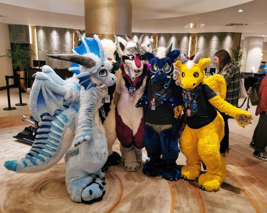 Four dragon fursuiters pose together in a hotel lobby at Confuzzled 2024: Arkie, Grace, Doran, and Azakir. Photo by Zelandeth.