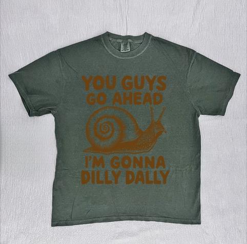 Greenish grey t-shirt with an illustrated snail between the words "You guys go ahead" and "I'm gonna dilly dally." Design by RetroRevealTshirts.