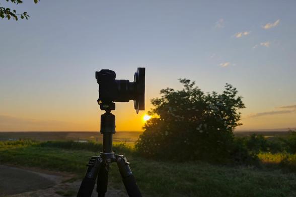 Canon M50 mit Filterhalterung vor aufgehender Sonne und Holunderbusch