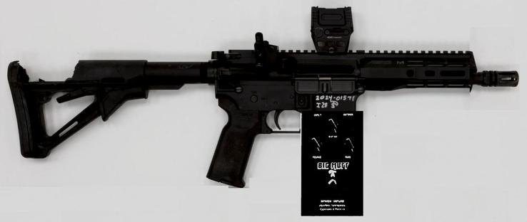 assault rifle with damaged shoulder stock and a scope mounted. Instead of the magazine, some musical equipment (probably a distortion device) is mounted onto the rifle
