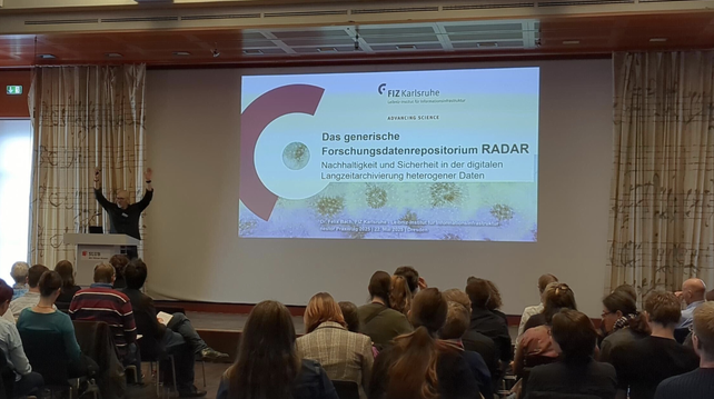 Our colleague Felix Bach presenting with arms raised high at the Nestor Praxistage 2025 in Dresden.