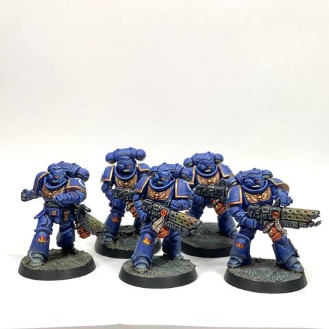 Five Space Marines with flame throwers. They wear bulky blue armor and aim their heat-bloomed weapons to their left. One is throwing a grenade.