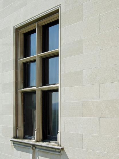 Color photo looking obliquely at a window - set into a finely dressed ashlar wall - which is divided into six sections by a stone mullion and four stone muntins