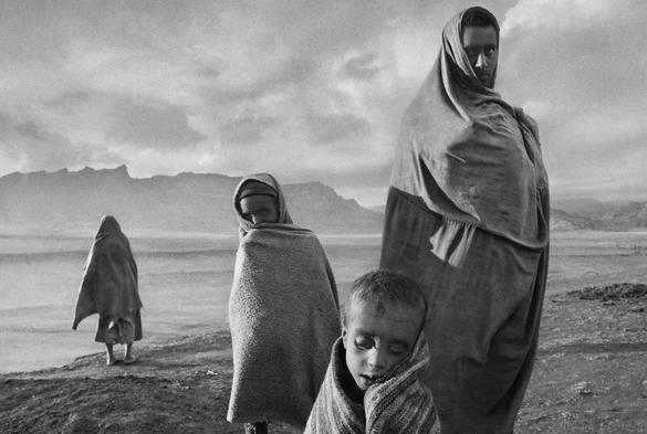 Photo by Patrick Witty on May 23, 2025. May be a black-and-white image of 1 person, child, cloak, head covering, headscarf and text.