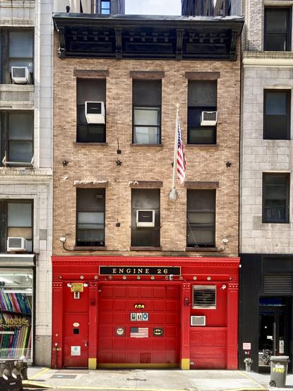 Fire station squeezed between lager buildings in New York. Tiny hydrant sits beside it.
