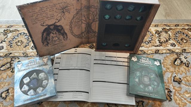 A dive box standing up open to reveal the dice in a foam tray with a character book below and a couple of dice sets either side.