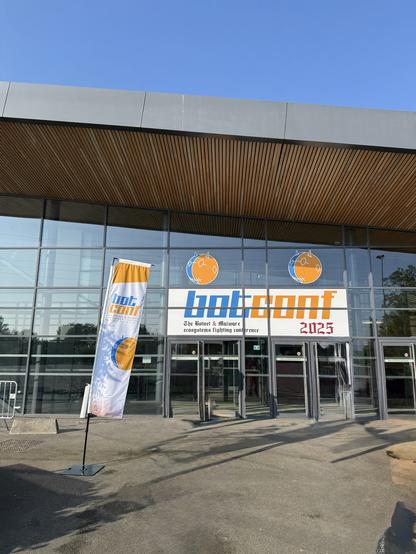 Entrance of the Botconf 2025 conference building in Angers, with a sunny blue sky (and some light AI removal of a couple of folks walking in front to preserve their privacy).