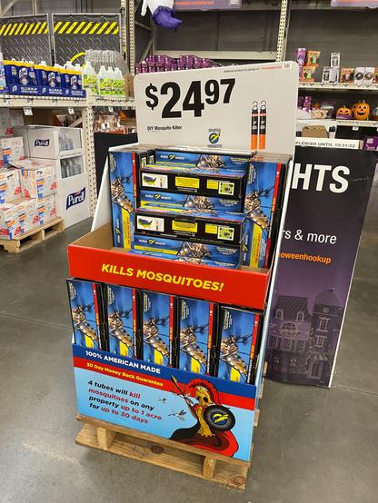 Store display of boxes of Spartan Mosquito Pro Techs, with various claims such as "kill mosquitoes on any property up to 1 acre for up to 30 days" and "100% American made." Each box has a photograph of a mosquito on it. $24.97 per box.