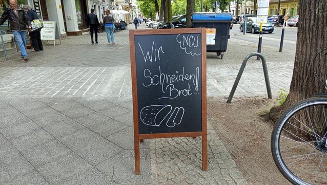 Tafel mit der Aufschrift: Neu: wir schneiden Brot.