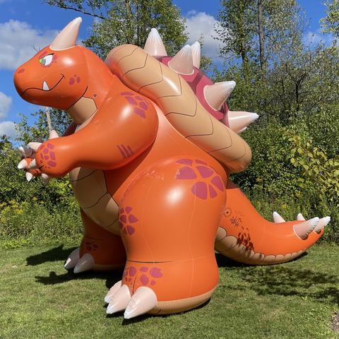 A photograph of an orange and red inflatable horned turtle of unusual size.