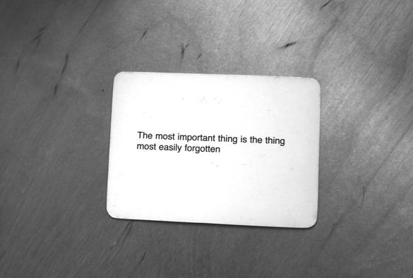 A black-and-white photo of an Oblique Strategy card. The card reads: 'The most important thing is the thing most easily forgotten'.