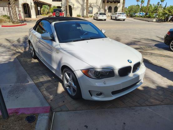 My new-to-me 2013 E88 128i convertible, bought with 73,000 miles on the odometer in January of this year. Seen from eye level from the front right passenger side, this last year of the Chris Bangle era 1-series, is also white, like the E30, although this is the current generation of the same color, Alpine White III. Alas, blue was not an available color for interior or top; this car has a tan interior and black fabric top (not cursed with the ponderous flanks used to shoehorn a retractable hardtop configuration onto its larger contemporary, the sad-looking E90 convertible.)

The 5-spoke wheels are the factory originals. The Bangle years were not good ones for BMW overall (I think his Z4 roadster is the ugliest BMW ever made) but this 1-series, too tall for its length, kinda stubby, is oddly endearing to me, like a goofy-looking beloved dog or cat. 

And the glorious smoothness of a BMW inline 6 feels like a more powerful version of its ancestor that was in my wonderful E30.