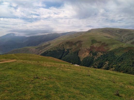 تصویری از کوهستان سرسبز روستای اسب ونی در مرتفع‌ترین منطقه جاده اسالم به خلخال. شامل کوه های پوشیده از سبزه و آسمان نیمه ابری.