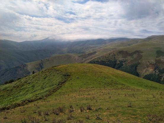 تصویری از کوهستان سرسبز روستای اسب ونی در مرتفع‌ترین منطقه جاده اسالم به خلخال. شامل کوه های پوشیده از سبزه و آسمان نیمه ابری.