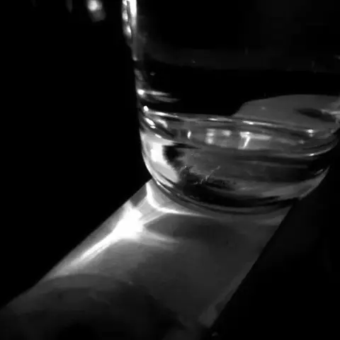 A photo of a glass reflecting light on a table in black and white.