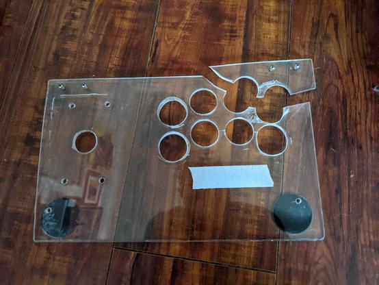 Clear acrylic plate. Many holes in different sizes at uneven angles and patterns

The top right corner has snapped off completely, cutting the two top right button holes in half