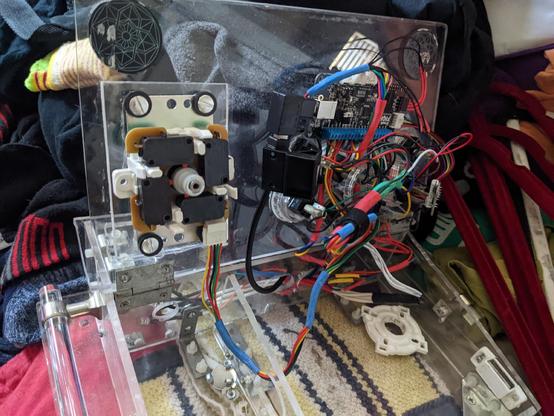 Top view photo of an arcade style Fight stick, made from clear acrylic save the wires, buttons, and PCB.

The fact plate has been flipped up to provide a better look at the internals.

All the PCBs and wires are mounted on the under side of the face plate