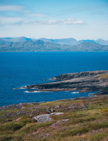 A view of layers of coastline and sea cliffs. Mixes of blues, yellows, greens, and browns.