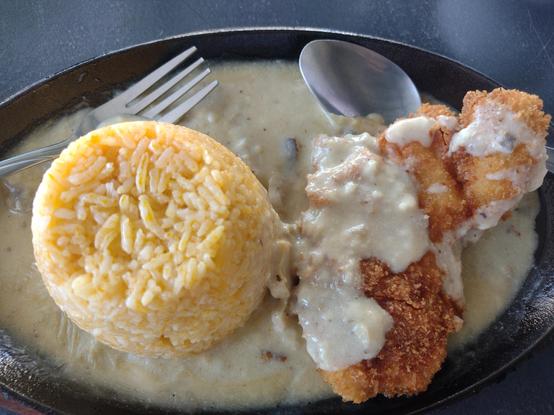 Closeup of Sizzling Chicken. Fried chicken breast with creamy sauce with java rice on a hot plate.