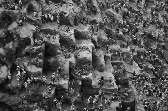Image of the Serra Pelada Gold Mine, Brazil, with hundreds of workers manually bringing sacks up out of the depths.