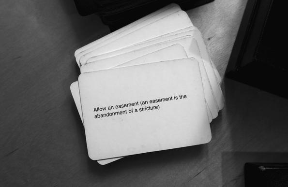 A black-and-white photo of an Oblique Strategy card. The card reads: 'Allow an easement (an easement is the abandonment of a stricture)'.
