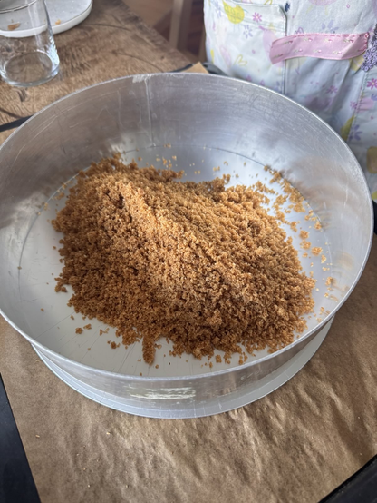 A pile of crushed homemade graham crackers at the bottom of a springpan.