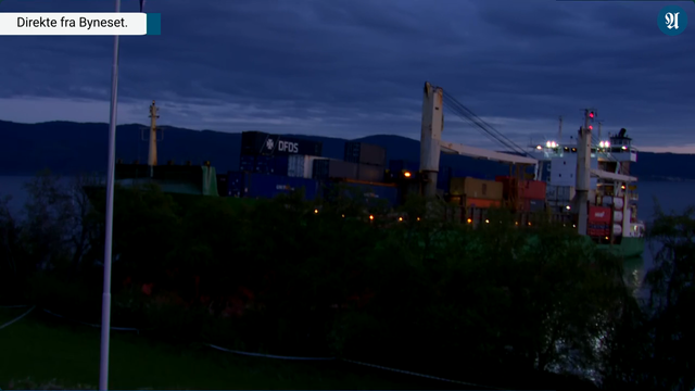 Screenshot of a live video feed showing a container ship run aground. It is quite dark and the vessel's lights are on.