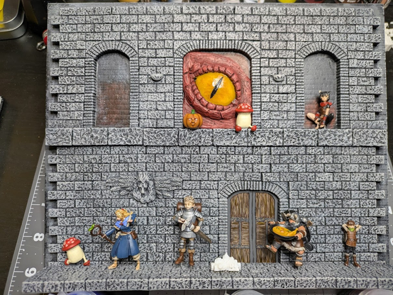 The model dungeon floor and wall, now painted. The Delicious in Dungeon characters are laid onto the piece to give a better representation of what the end piece will look like.